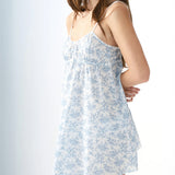 Woman wearing a light blue floral dress against a white background
