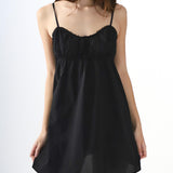 Black slip dress worn by a model on a white background