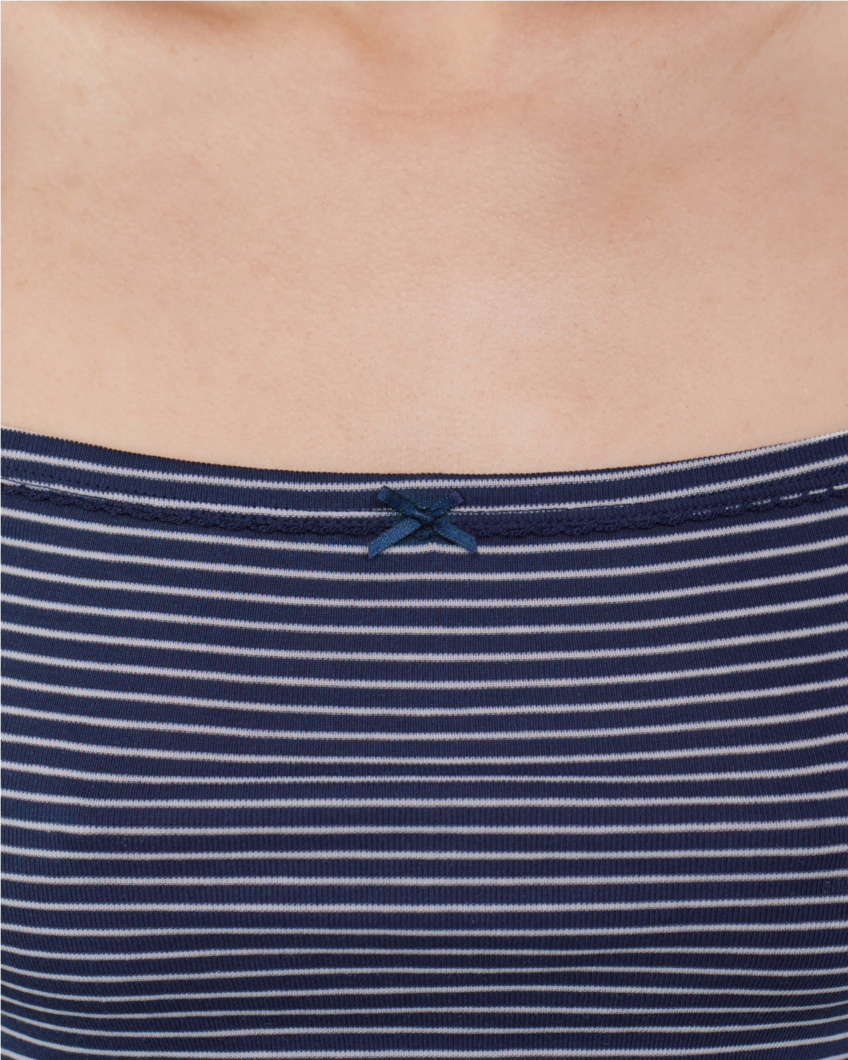 Close-up of a navy blue and white horizontally striped ribbed top with a small navy bow at the neckline, worn by a model.