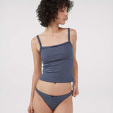A model wearing a navy blue and white striped tank top and thong photographed against a light gray studio background.