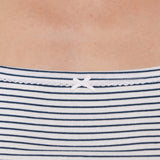 Close-up of a person wearing a white top with thin navy horizontal stripes and a small white bow at the neckline.