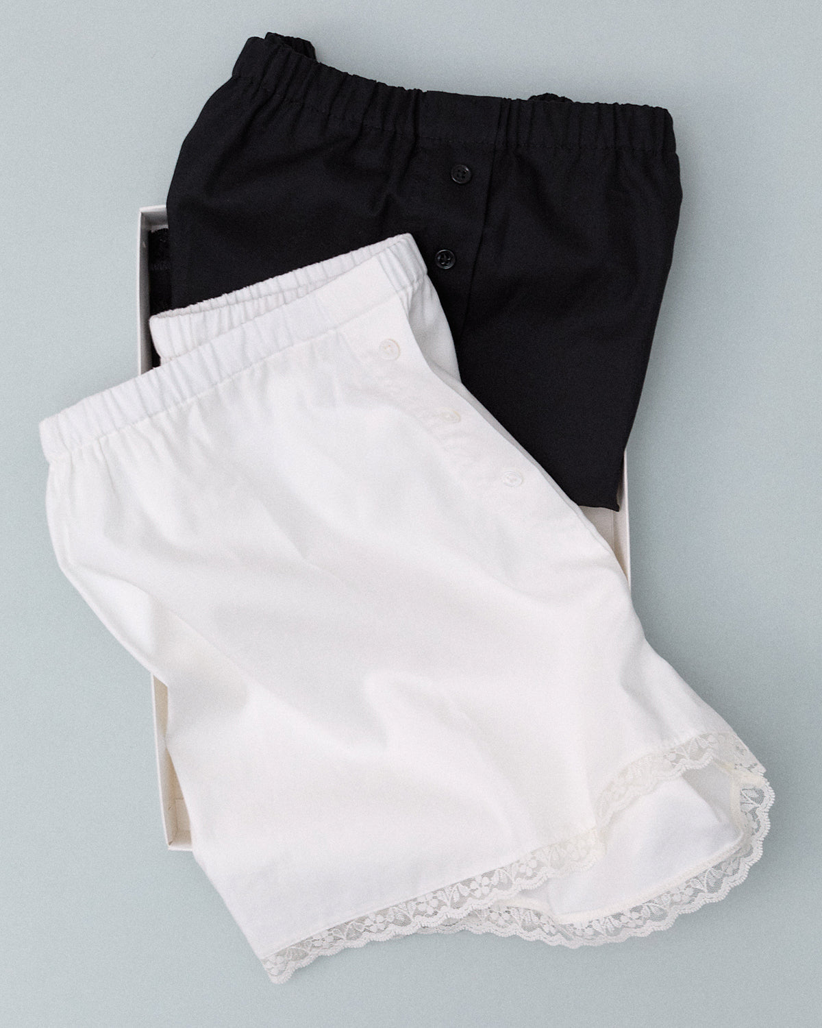 Black and white shorts with lace trim on a light gray background