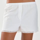 White shorts with lace trim worn by a person on a light background