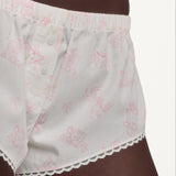 Close up of woman wearing white shorts with a pink pattern and lace trim. 