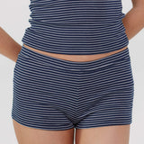 Close-up of a model wearing navy blue and white horizontally striped shorts and a matching striped top against a light gray studio background.