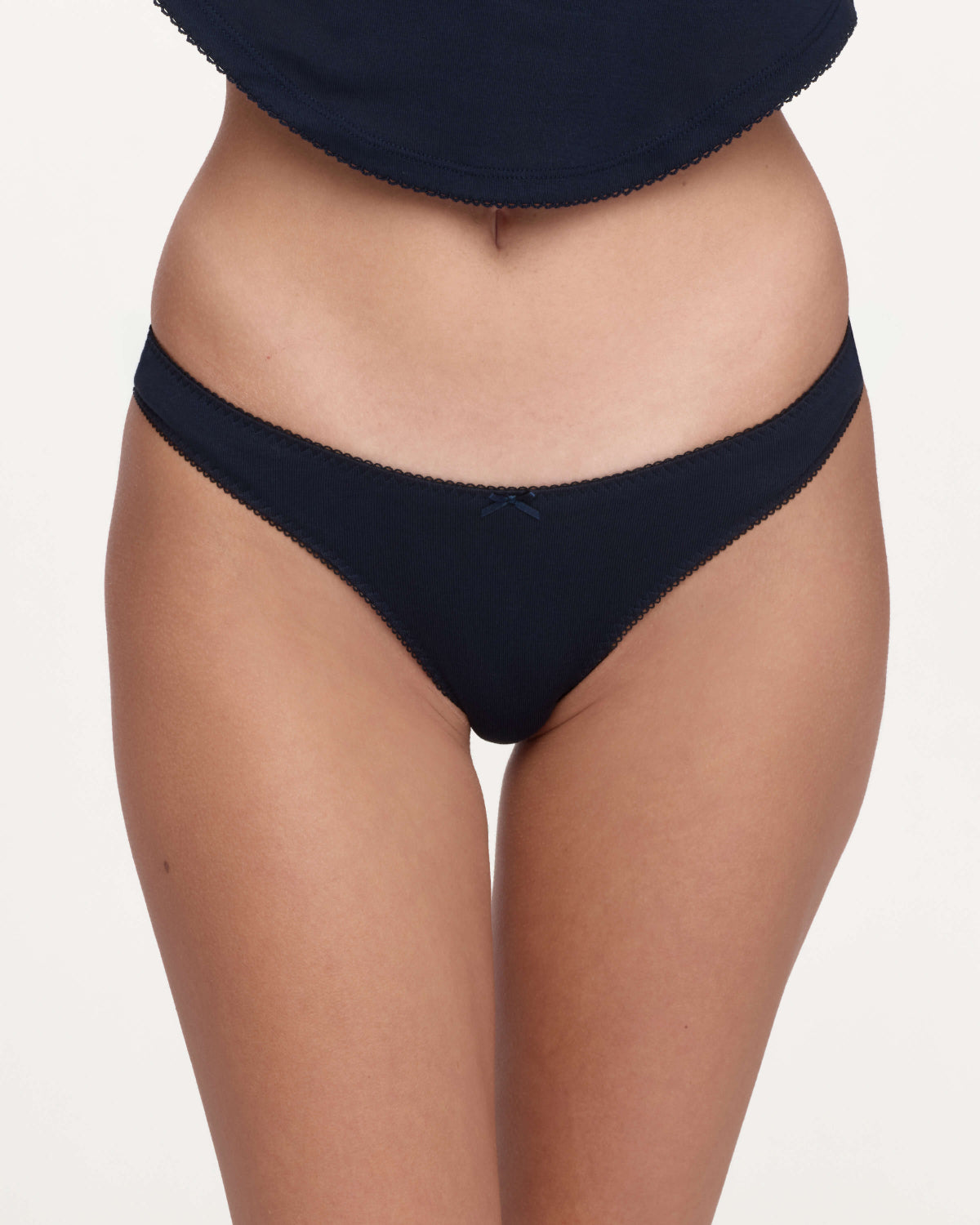 A close-up of a model wearing a pair of dark navy blue underwear against a plain light background.