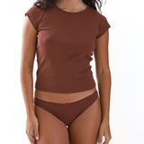 Woman wearing a brown cap sleeve top and brown brief on a white background