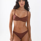 Woman wearing a brown bra and brief underwear set on a white background