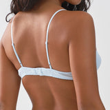 Woman wearing a light blue bra against a white background