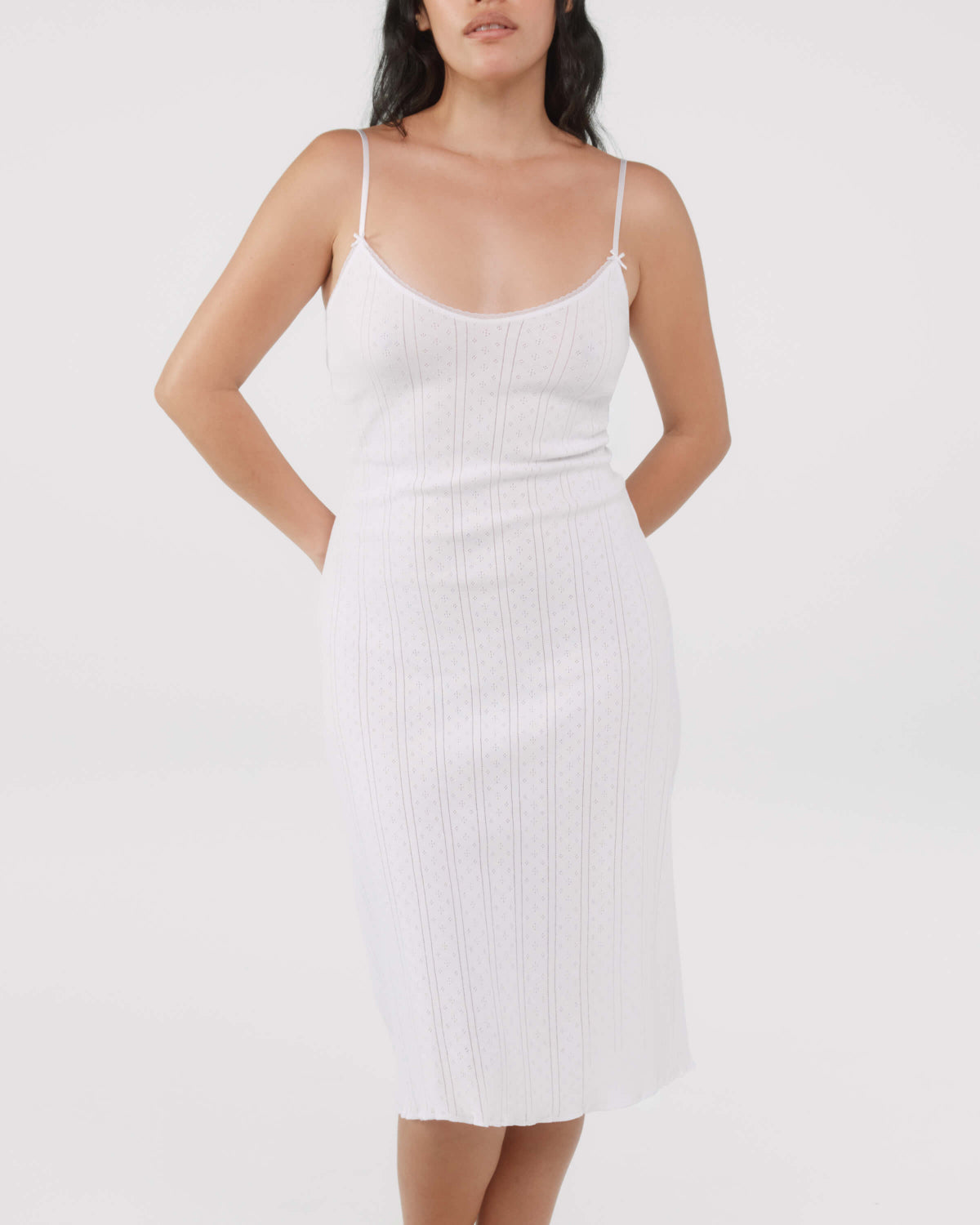 Woman wearing a white slip dress against a plain background