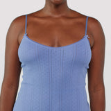 Woman wearing a blue spaghetti strap dress against a white background