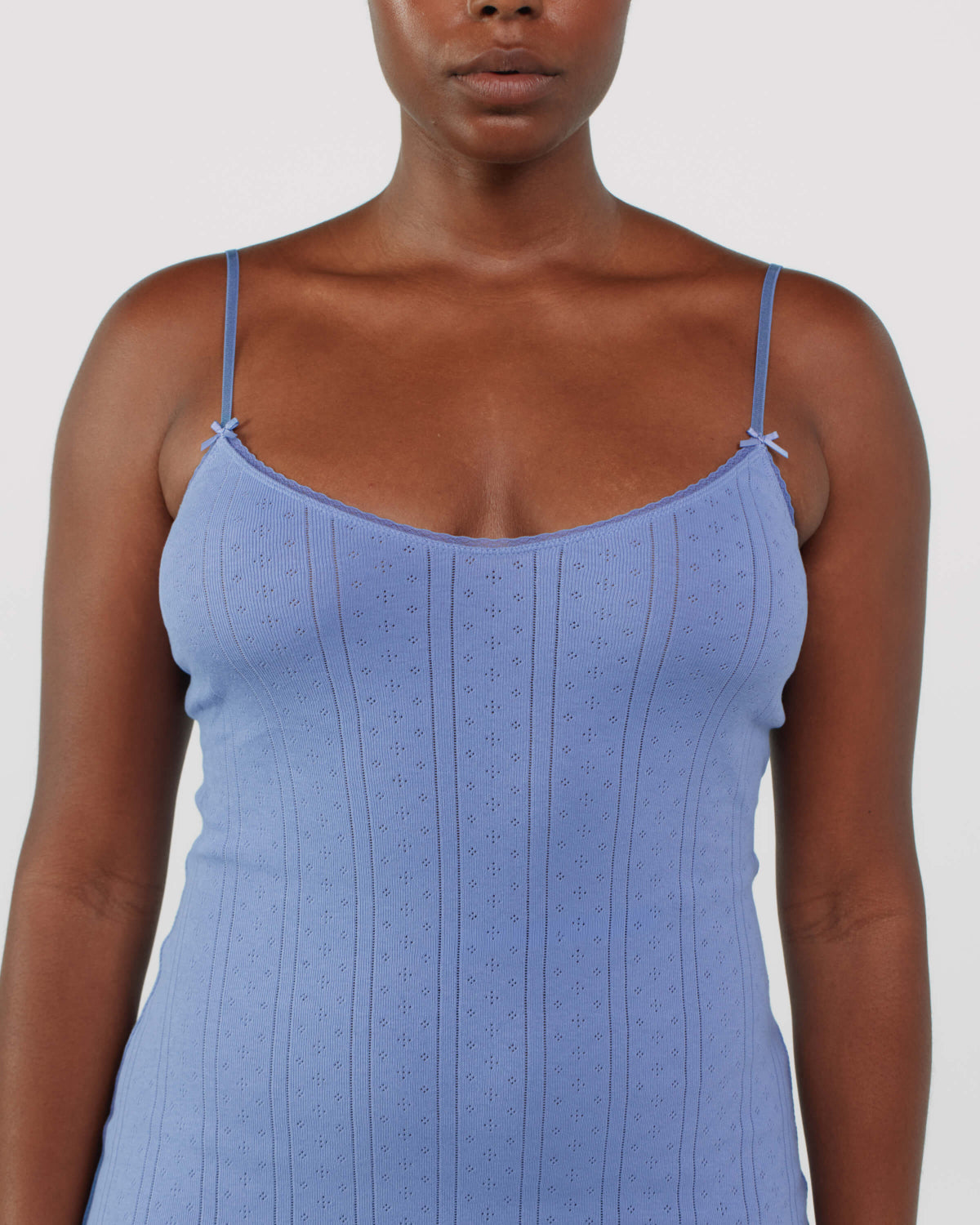 Woman wearing a blue spaghetti strap dress against a white background