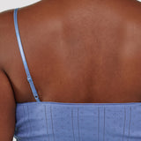 Blue dress with thin straps worn by a person on a white background