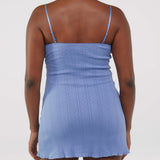 Person wearing a blue dress with thin straps on a plain background