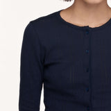 Close-up of a model wearing a dark navy ribbed knit long-sleeve top with a buttoned front and scalloped neckline.