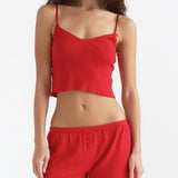 Woman wearing a red crop top and shorts on a white background