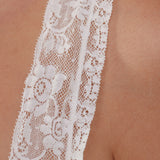 Close-up of white lace trim on a skin-toned background