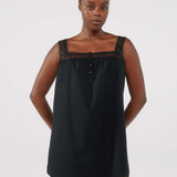 Woman wearing a black sleeveless dress with lace details on a white background