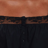 Black dress with lace trim on a brown background