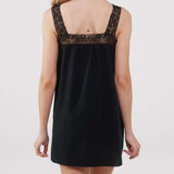 Black slip dress with lace detailing on a plain background