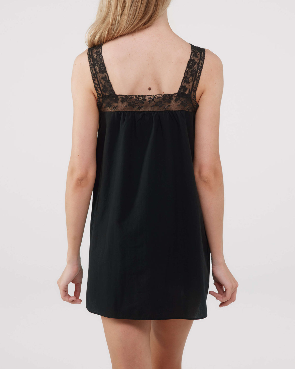 Black slip dress with lace detailing on a plain background