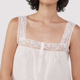 White lace-trimmed dress worn by a person on a white background
