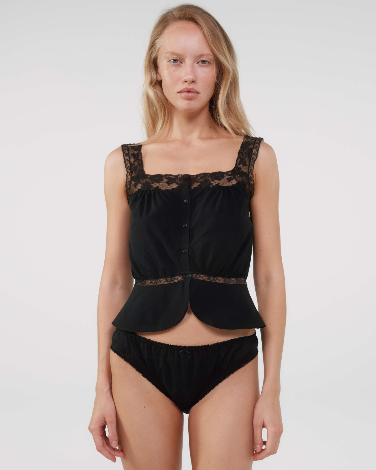 Woman wearing a black lace top and underwear set on a white background