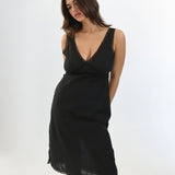 Woman wearing a black slip dress against a white background