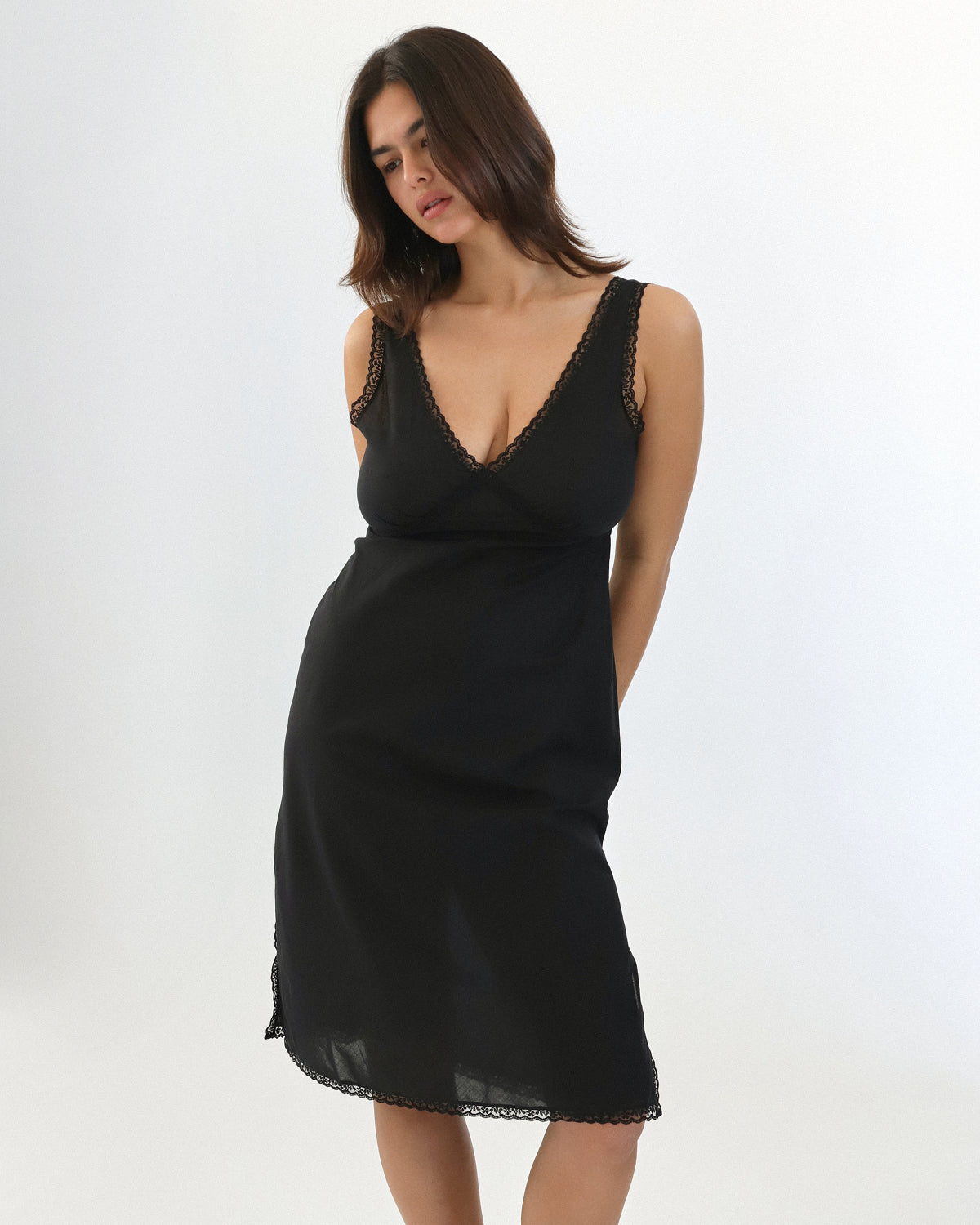 Woman wearing a black slip dress against a white background