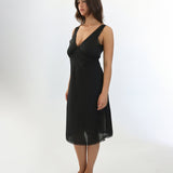 Woman wearing a black slip dress on a white background