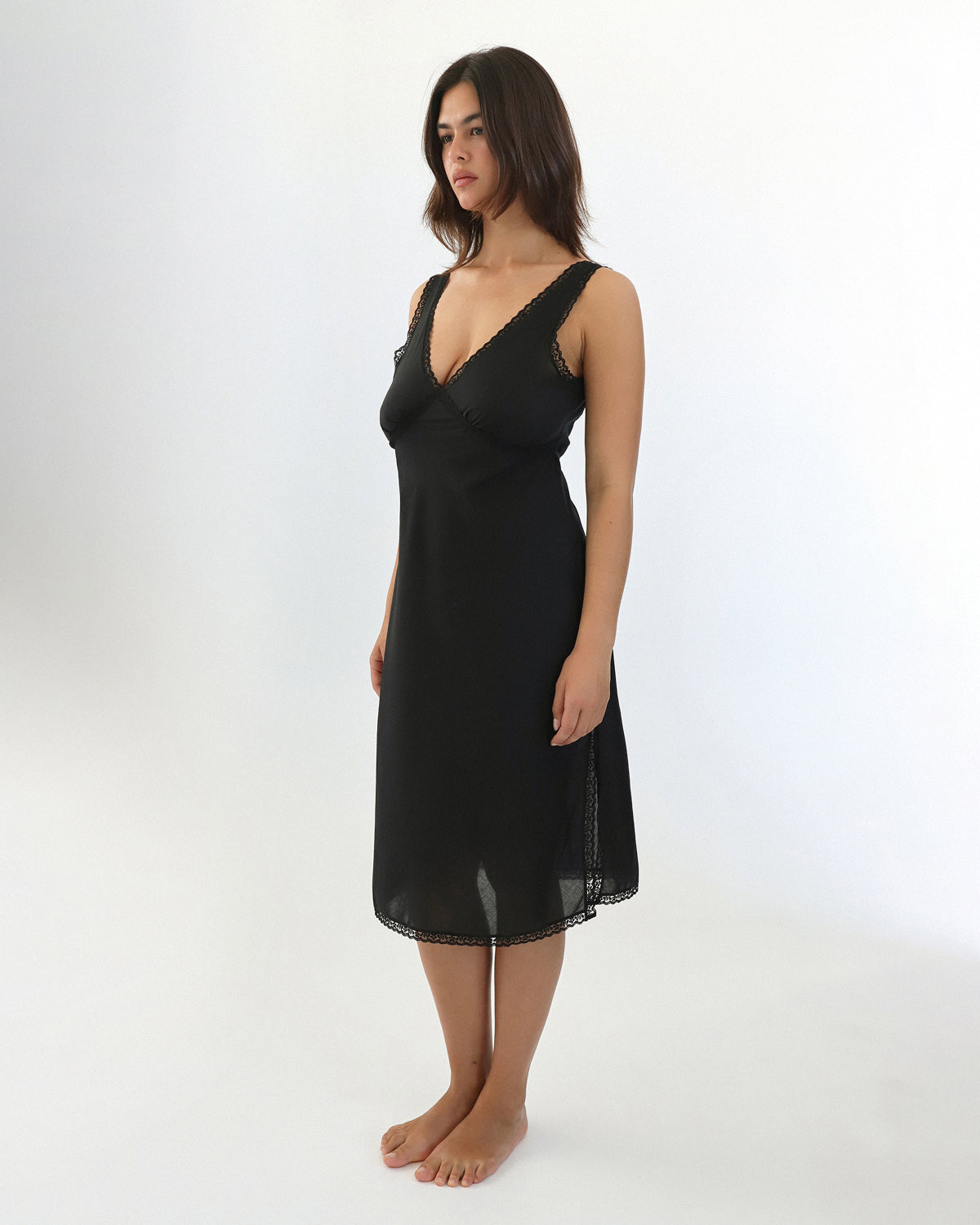 Woman wearing a black slip dress on a white background