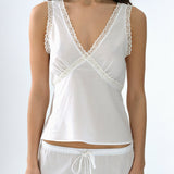 White lace-trimmed top worn by a person on a white background