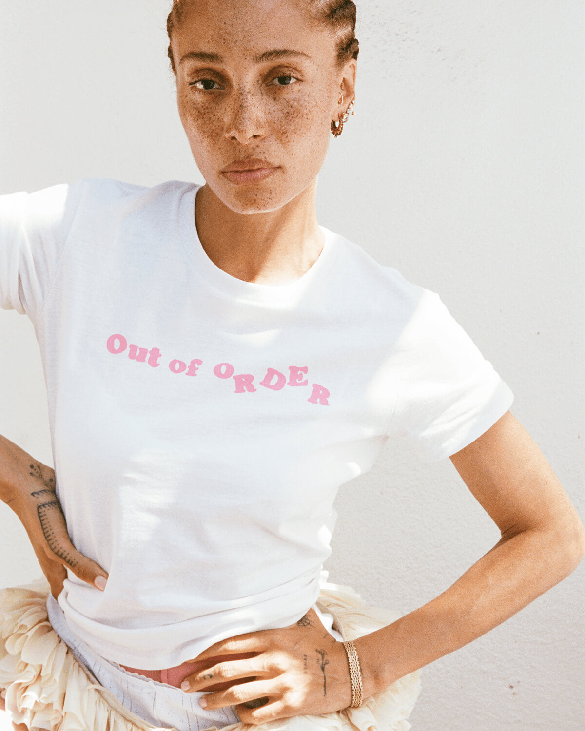 Person wearing a white t-shirt with 'Out of Order' text in pink on a plain background