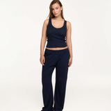 A woman modeling a matching navy blue lounge set consisting of a ribbed tank top and wide-leg pants, standing against a plain white studio background.