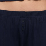 Close-up of a person wearing dark navy pants with a three-button placket and a matching cropped top.