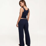 A woman modeling a matching navy blue loungewear set, featuring a cropped tank top and wide-leg pants, shown from a rear angle against a plain white studio background.