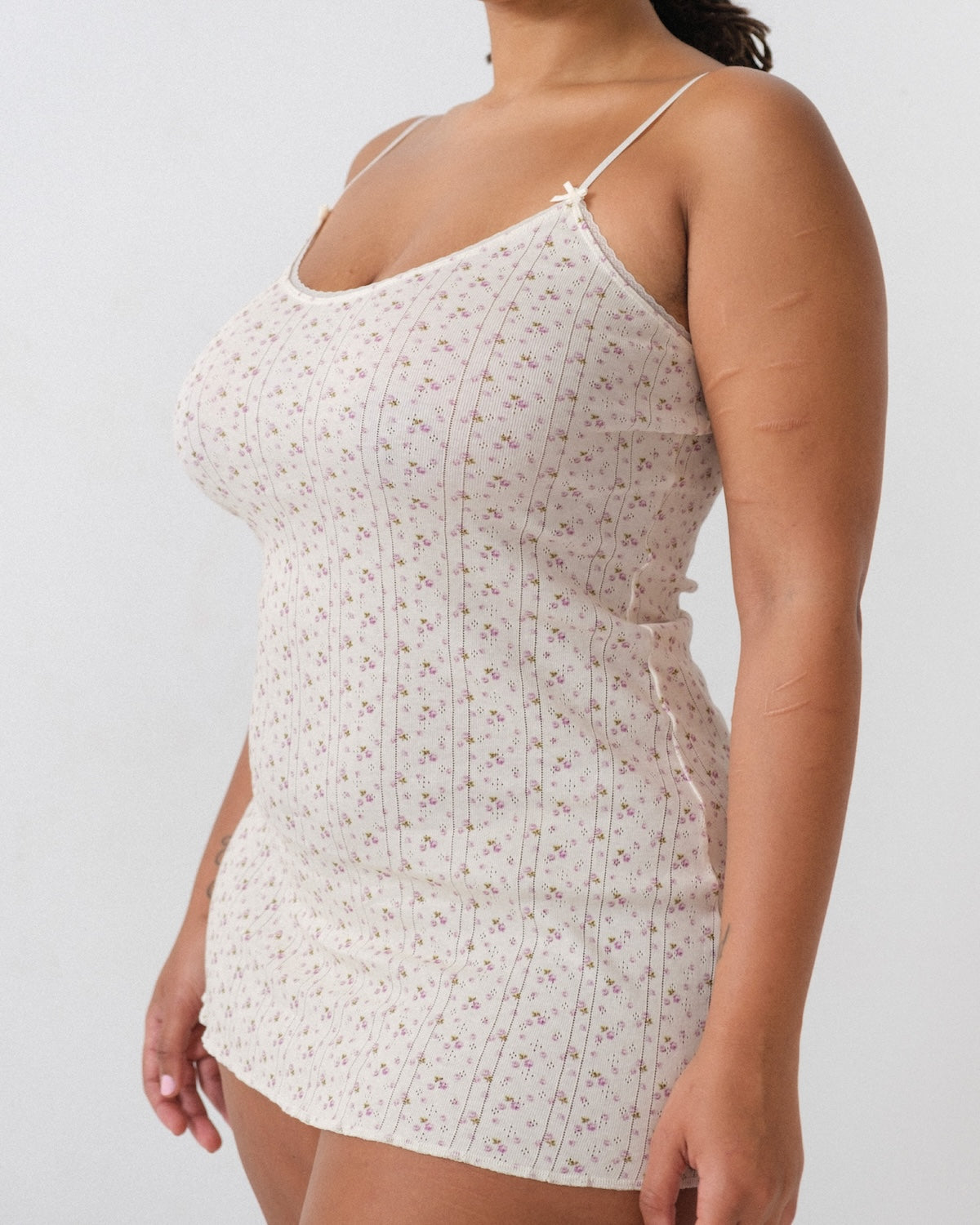 White floral dress worn by a person on a plain background
