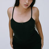 Woman wearing a black tank top against a plain background
