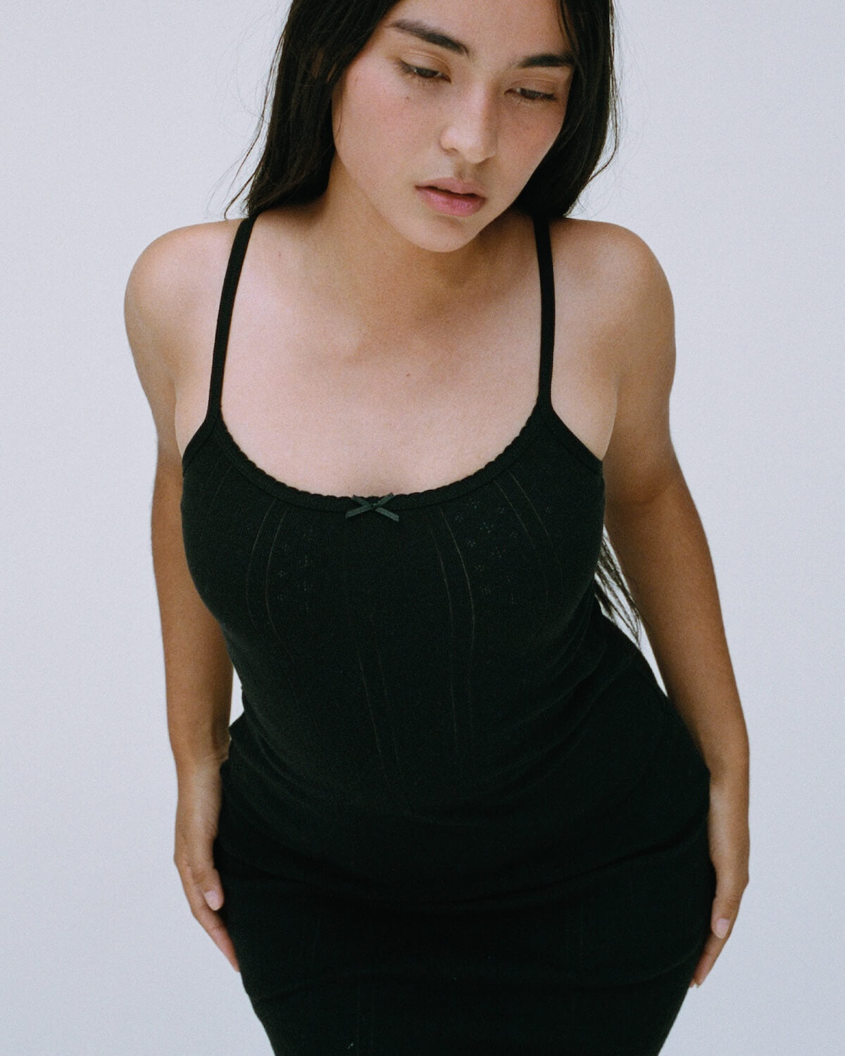 Woman wearing a black tank top against a plain background