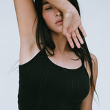Woman wearing a black tank top against a plain background
