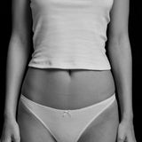 Person wearing a white t-shirt and light-colored underwear against a black background