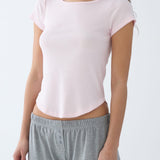 Person wearing a light pink top and gray pants on a white background