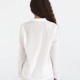 Person wearing a white blazer and pants on a plain background