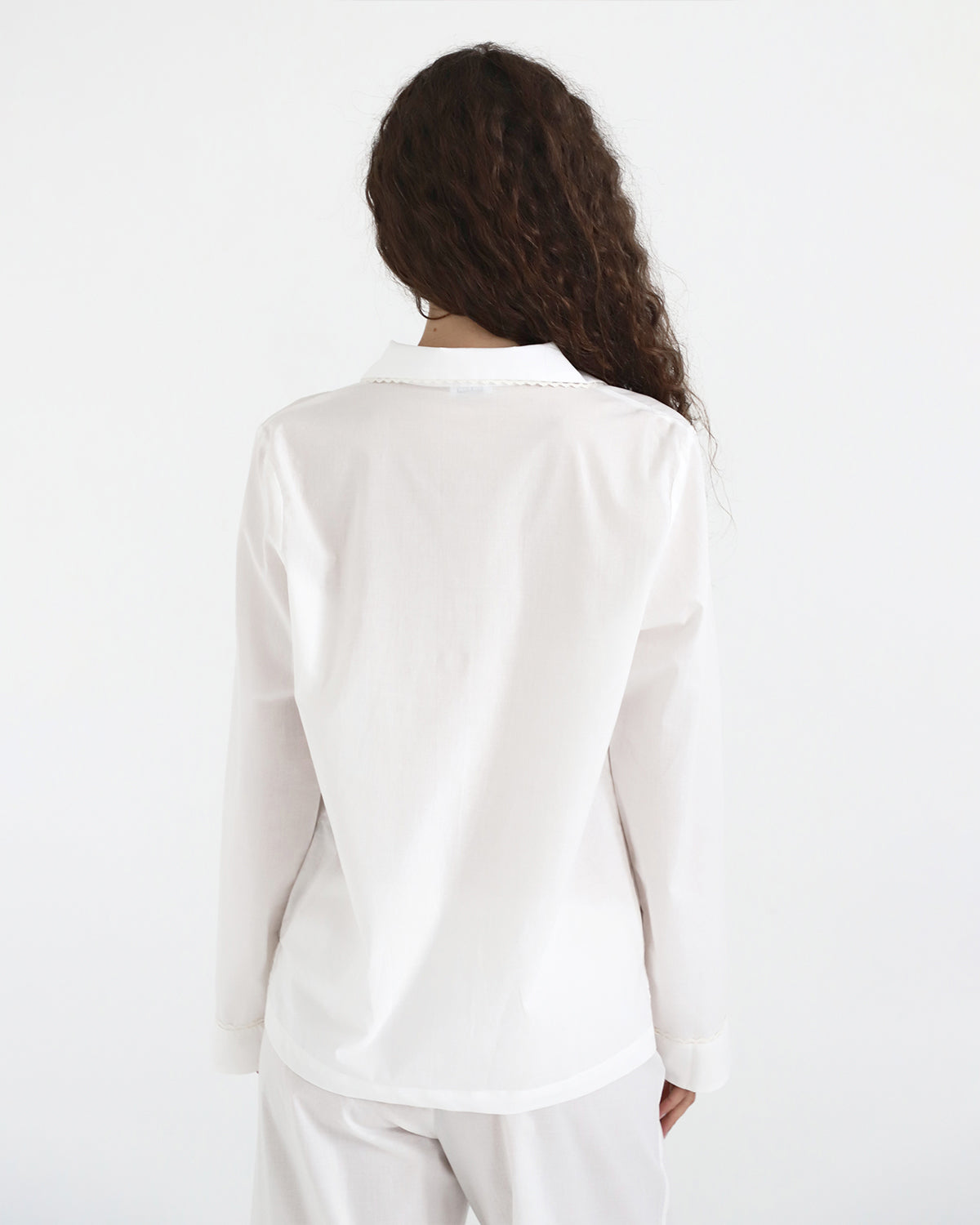 Person wearing a white blazer and pants on a plain background
