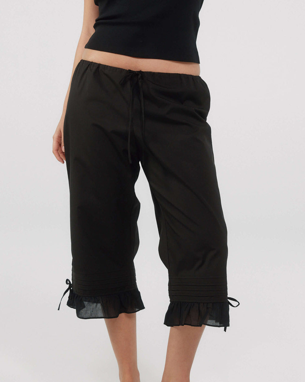 Black capri pants with ruffled hem on a white background