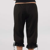 Person wearing black capri pants with ruffled cuffs on a white background