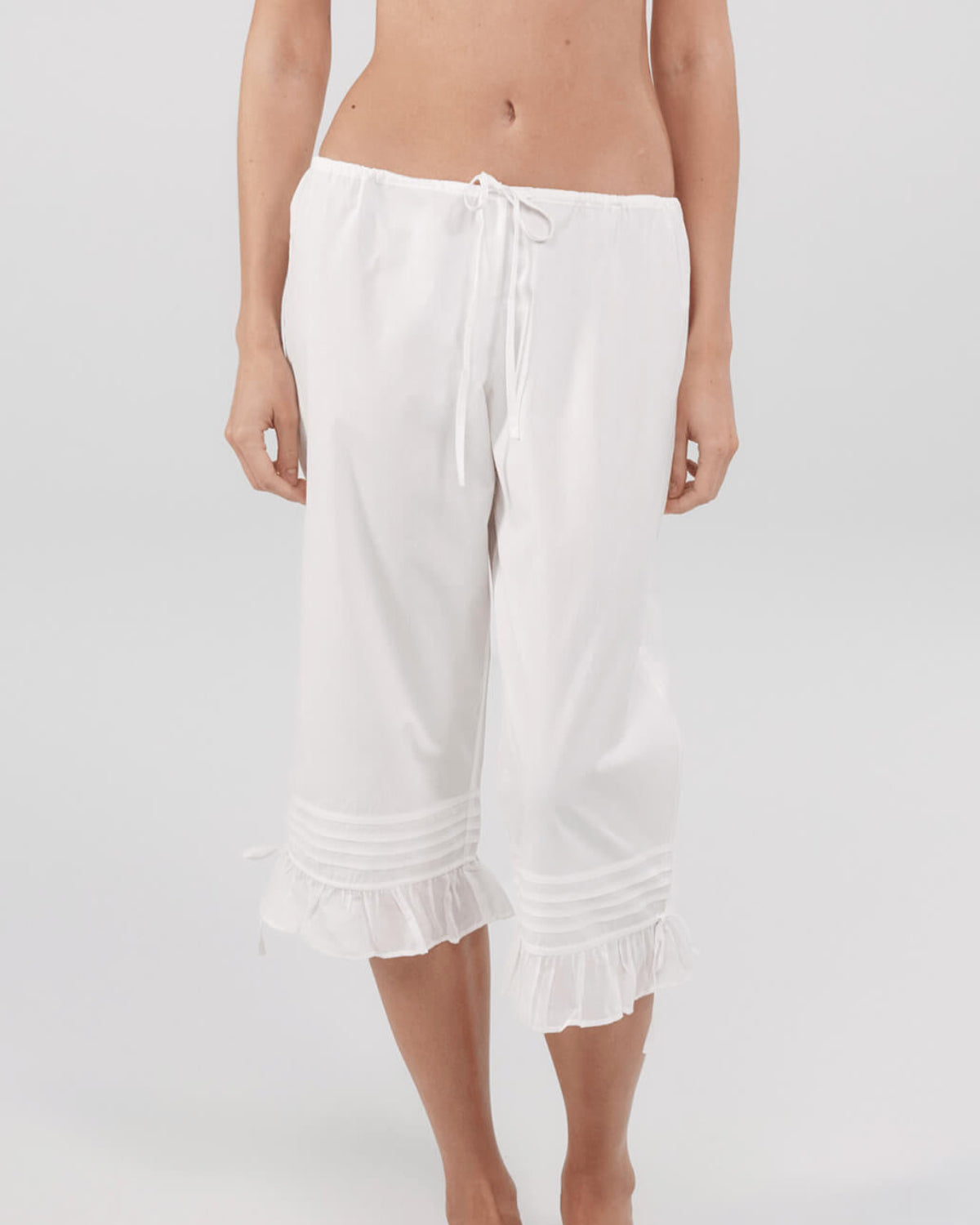 White capri pants worn by a person on a white background