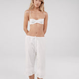 Woman wearing a white bra and pants on a plain background