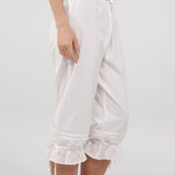 White ruffled pants worn by a person on a light gray background