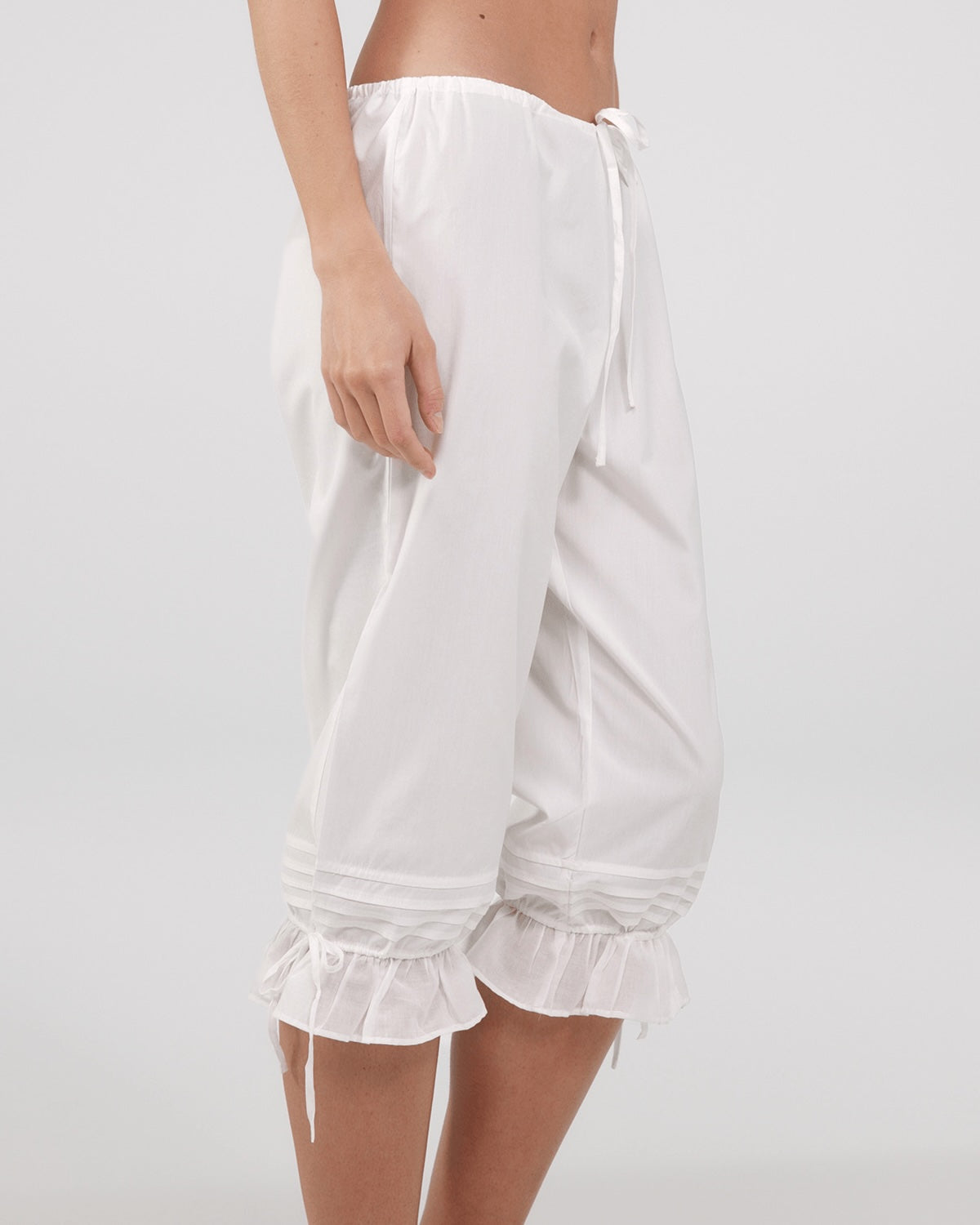White ruffled pants worn by a person on a light gray background